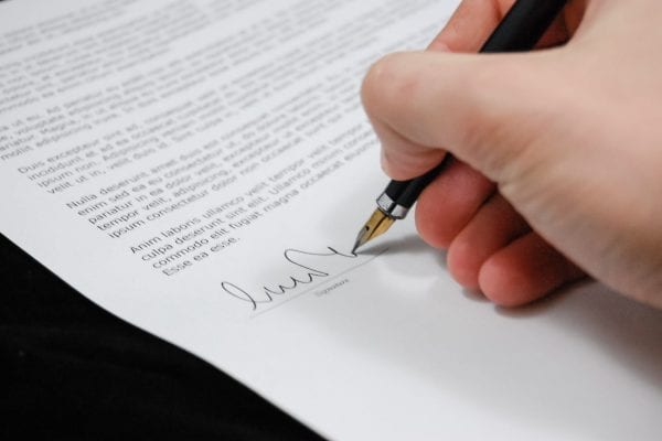 Hand holding a pen and signing a document