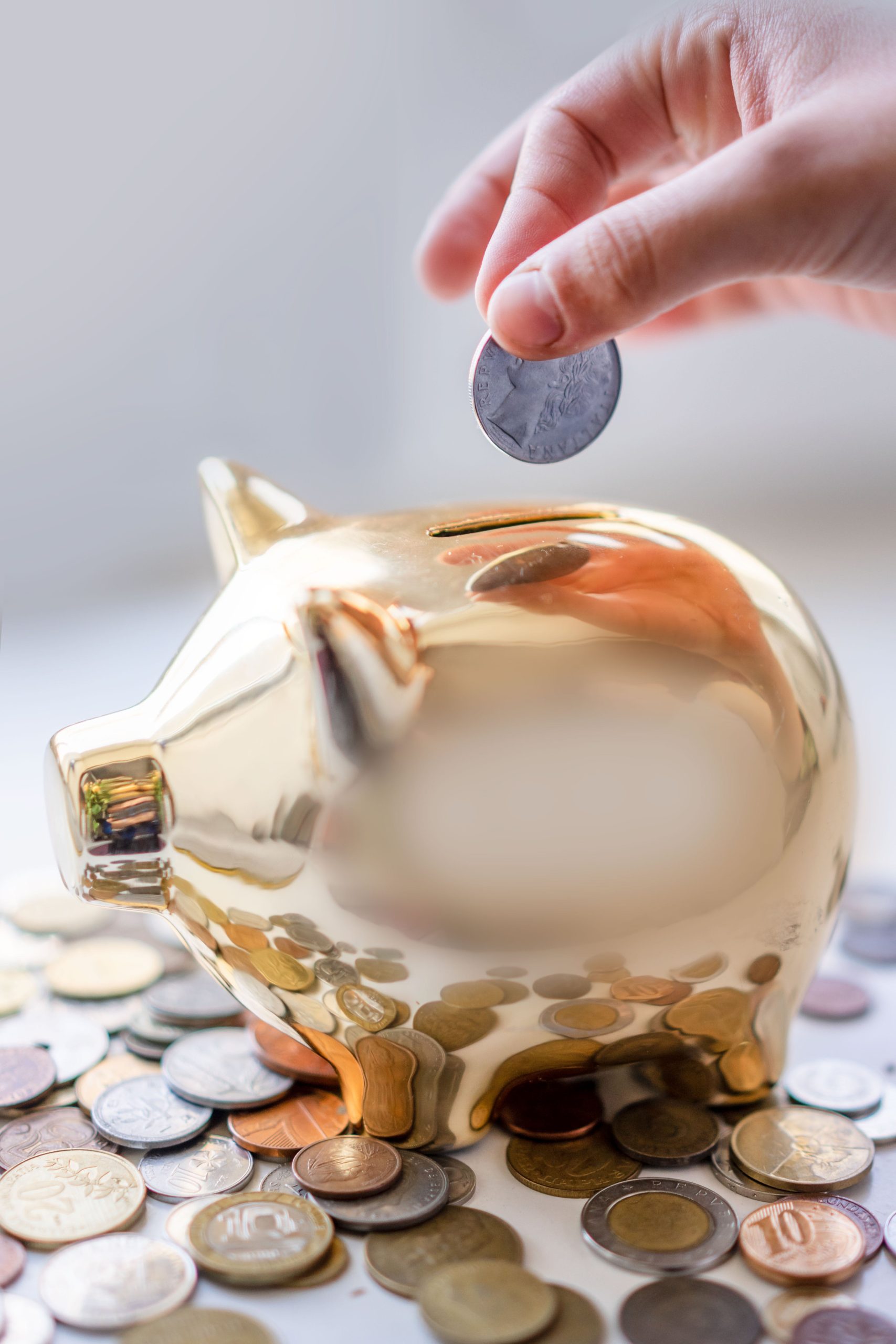 gold piggy bank with hand above it with a coin